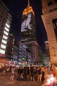 Pedestrians photograph a leopard projected on the Empire State Building as part of the “Projecting Change: The Empire State Building” project.
